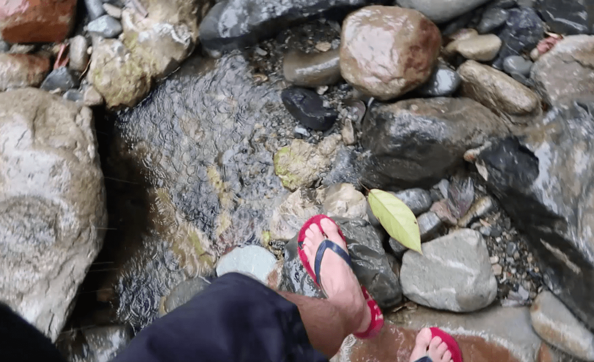 guy walking over wet rocks with slippers in catanduanes province philippines